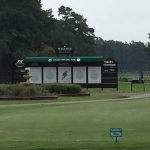 A long distance shot of a golf course and scoreboard