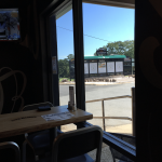 Inside a restaurant looking out at a golf scoreboard with black paint and green awning