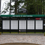 A black and white golf scoreboard with green overhang