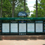 a brick pathway leads up to a golf scoreboard with advertising